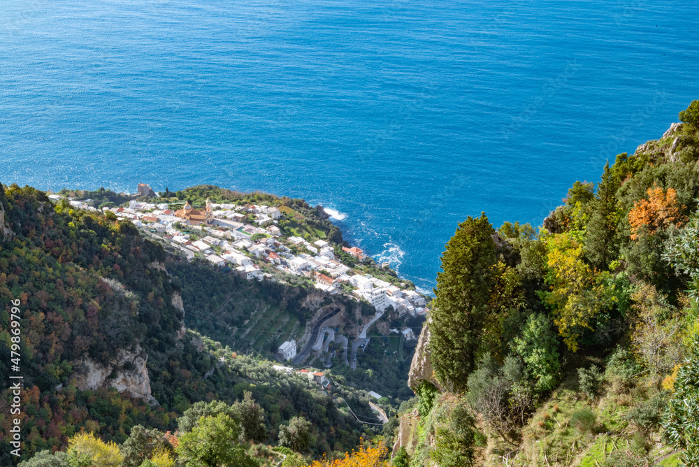 The Italian village of Praiano, seen from above, from the Path of the Gods (Sentiero degli Dei) along the scenic Amalfi Coast of Italy, with the blue Tyrrhenian Sea and blue sky and clouds