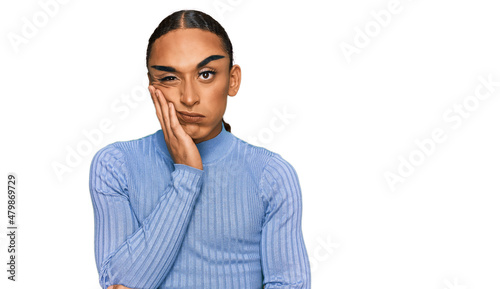 Hispanic transgender man wearing make up and long hair wearing casual clothes thinking looking tired and bored with depression problems with crossed arms.