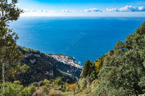 The Italian village of Praiano, seen from above, from the Path of the Gods (Sentiero degli Dei) along the scenic Amalfi Coast of Italy, with the blue Tyrrhenian Sea and blue sky and clouds photo