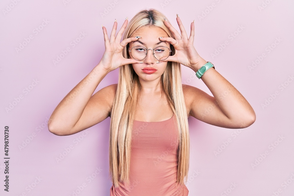 Young blonde girl wearing casual clothes trying to open eyes with fingers, sleepy and tired for morning fatigue