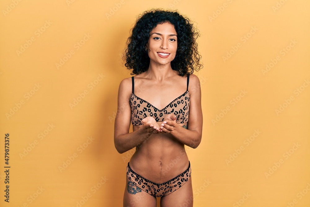 Young latin girl wearing bikini smiling with hands palms together receiving or giving gesture. hold and protection Young latin girl wearing bikini smiling with hands palms together receiving or giving gesture. hold and protection
