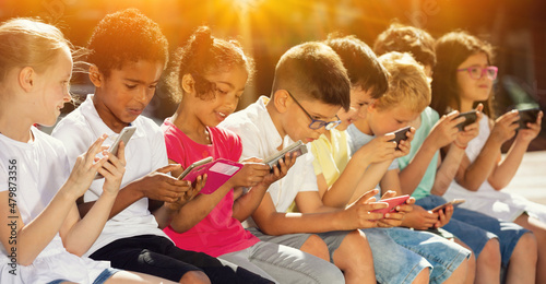 Eight kidsare chatting on their smartphone on walking. High quality photo