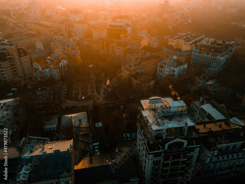 Aerial view from the drone on the roofs of houses and buildings at sunset in town