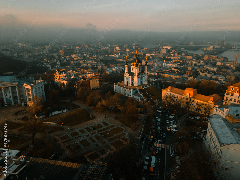 Aerial view from the drone on the roofs of houses and buildings at sunset in town