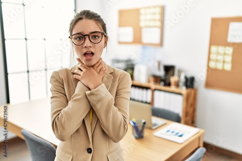 Young brunette teenager wearing business style at office shouting and suffocate because painful strangle. health problem. asphyxiate and suicide concept.
