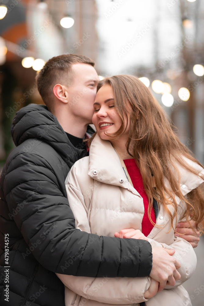 Naklejka premium A close-up photo of a girl and her boyfriend hugging and happily spending time together. The concept of light valentine's day, gifts