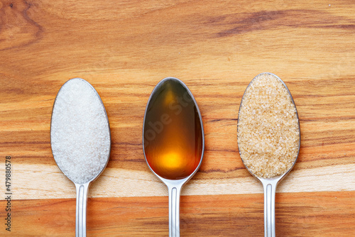 Konstfotografi High angle view of spoons full with white sugar, raw honey and brown sugar on wooden table