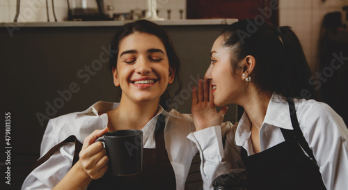 Close-up of a portrait of two young and beautiful business women sitting with coffee mugs chatting in a good mood while relaxing while working in a small business coffee shop.