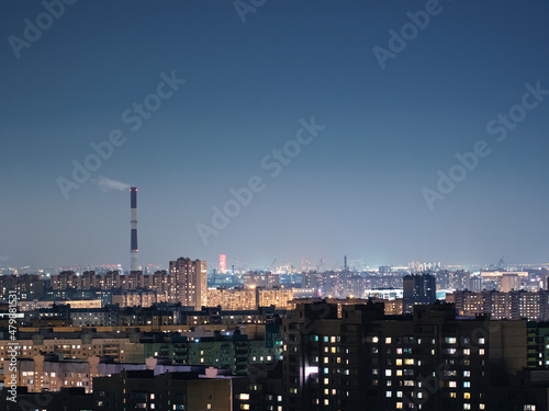 Smoking chimney above city buildings at the night. Urban landscape