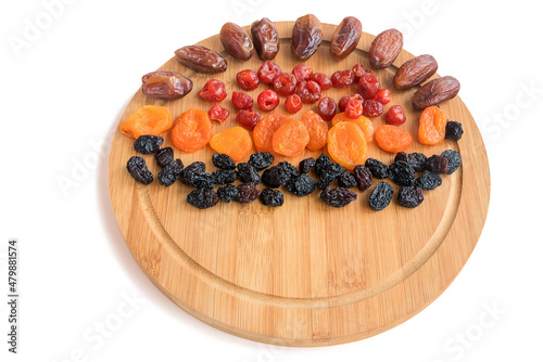 On a wooden cutting board are delicious healthy dried fruits, dates, dried cranberries, apricots, black raisins.  photo