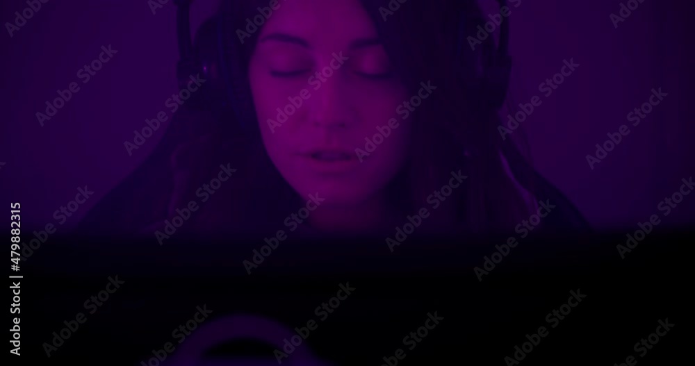 close up caucasian woman with headphones. Girl play video games and talk. Purple and pink light. close up caucasian woman with headphones. Girl play video games and talk. Purple and pink light.