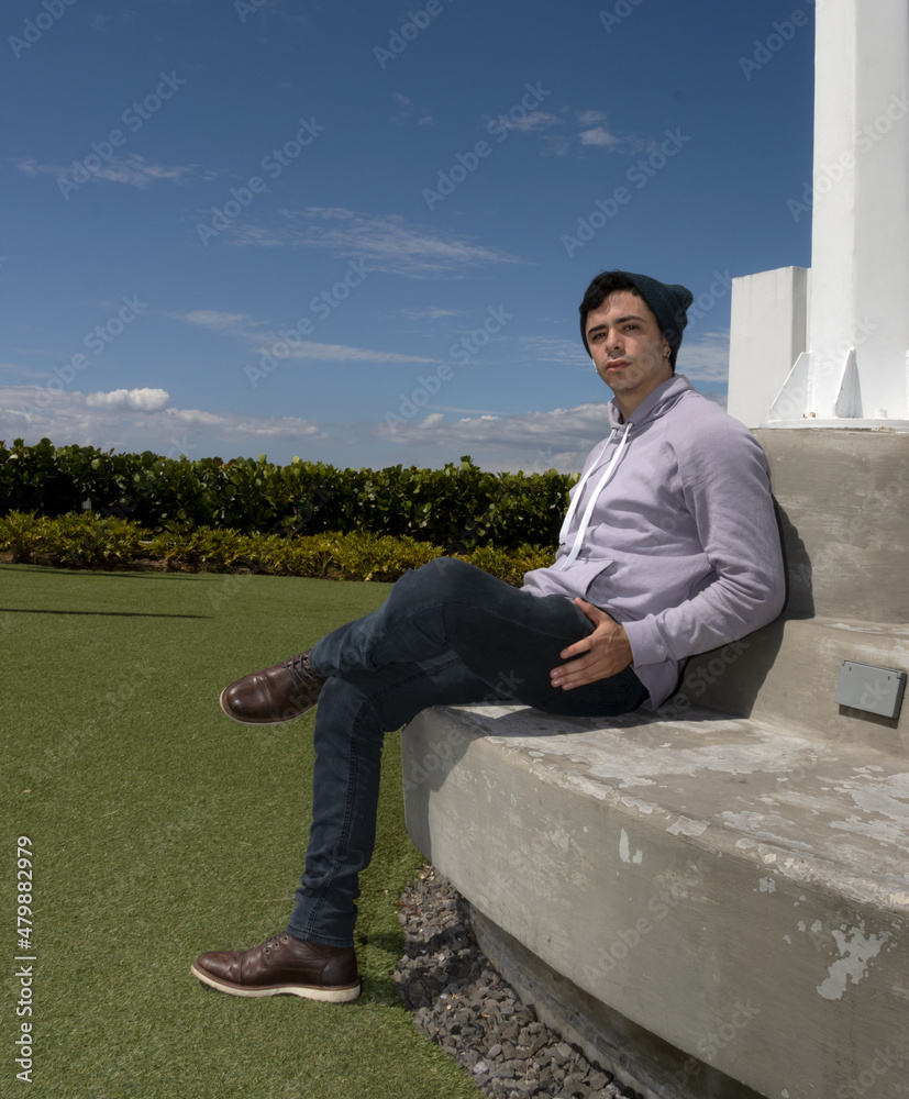 Independent young Latino man meditating, enjoying a sunset, reaching his goals, overcoming obstacles. Young man in his 20's using technology and clean energy. Engineer specialized in renewable energie