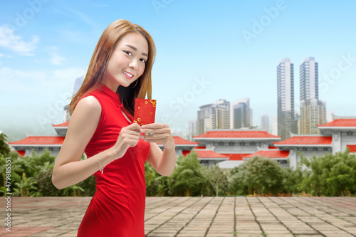 Asian Chinese woman in a cheongsam dress holding red envelopes photo