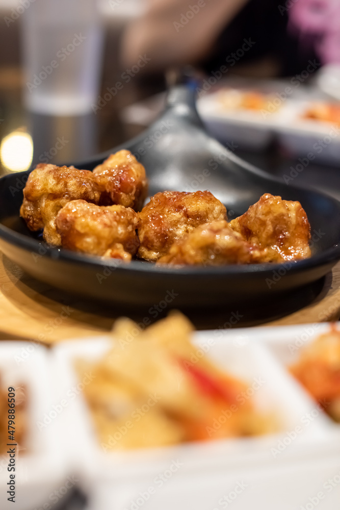 Fried chicken with soy sauce served on the black hot plate with kimchi on table. Traditional Korean Crispy Chicken in a modern Korean restaurant. Fried chicken with soy sauce served on the black hot plate with kimchi on table. Traditional Korean Crispy Chicken in a modern Korean restaurant.