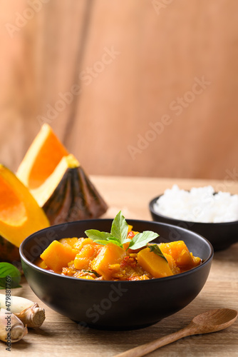 Thai spicy pumpkin curry soup with pork on wooden table photo