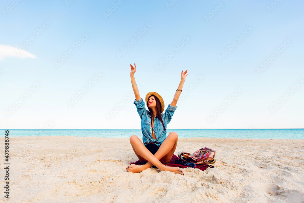 Gorgeous sexy woman with perfect tan body, full red lips and l long legs posing on the tropical sunny beach. Wearing crop top , shorts and straw hat. Bright sunny colors. Gorgeous sexy woman with perfect tan body, full red lips and l long legs posing on the tropical sunny beach. Wearing crop top , shorts and straw hat. Bright sunny colors.