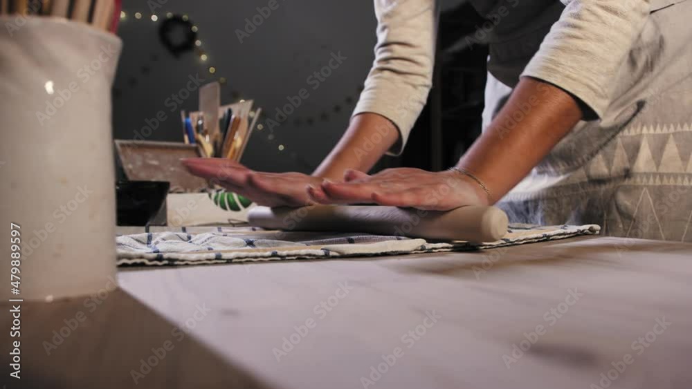 Pottery in the studio - young woman flattening clay using a rolling pin Pottery in the studio - young woman flattening clay using a rolling pin