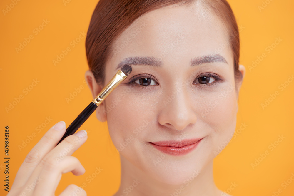 Portrait of a beautiful woman applying eye shadow