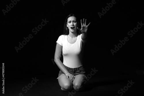 Scared young woman on dark ...