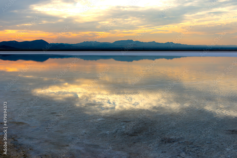 Fototapeta premium The sun shines behind the clouds above the lake