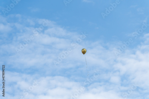 A golden balloon flew under the blue sky and white clouds