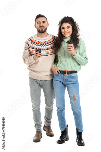 Happy young couple in warm sweaters and with coffee on white background