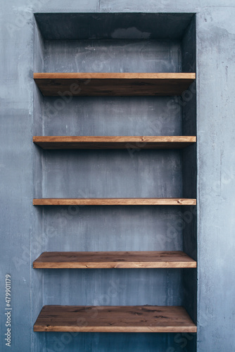 Empty wood shelves at concrete wall in home interior.