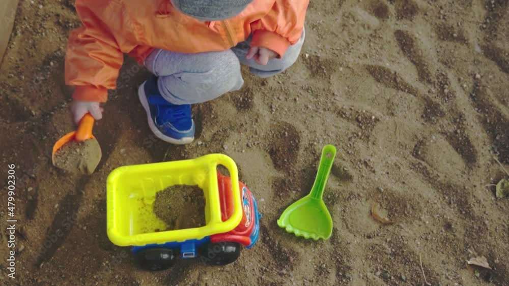 boy playing in the sandbox. A children's sand truck is rolling. slow motion. boy playing in the sandbox. A children's sand truck is rolling. slow motion.