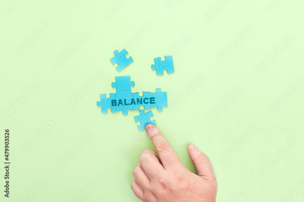 A man connecting the puzzle pieces with the word Balance A man connecting the puzzle pieces with the word Balance