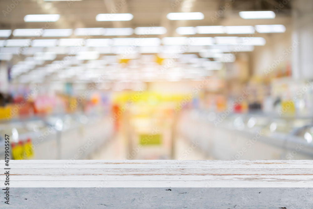 Wooden board empty table in front of of supermarket shelves. Perspective white wood over blur in supermarket Wooden board empty table in front of of supermarket shelves. Perspective white wood over blur in supermarket