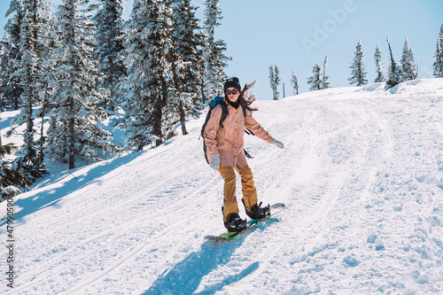 Russia. Sheregesh. Girl snowboarder in sun goggles in winter in sunny weather outdoors among the mountains and snow. Spring. The girl rides a snowboard. Sport