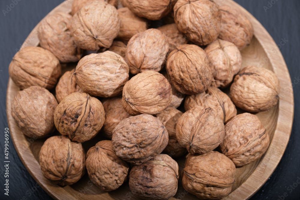 Walnut on black top view. Group of walnuts on a black background. Nuts on a wooden plate. Walnut on black top view. Group of walnuts on a black background. Nuts on a wooden plate.