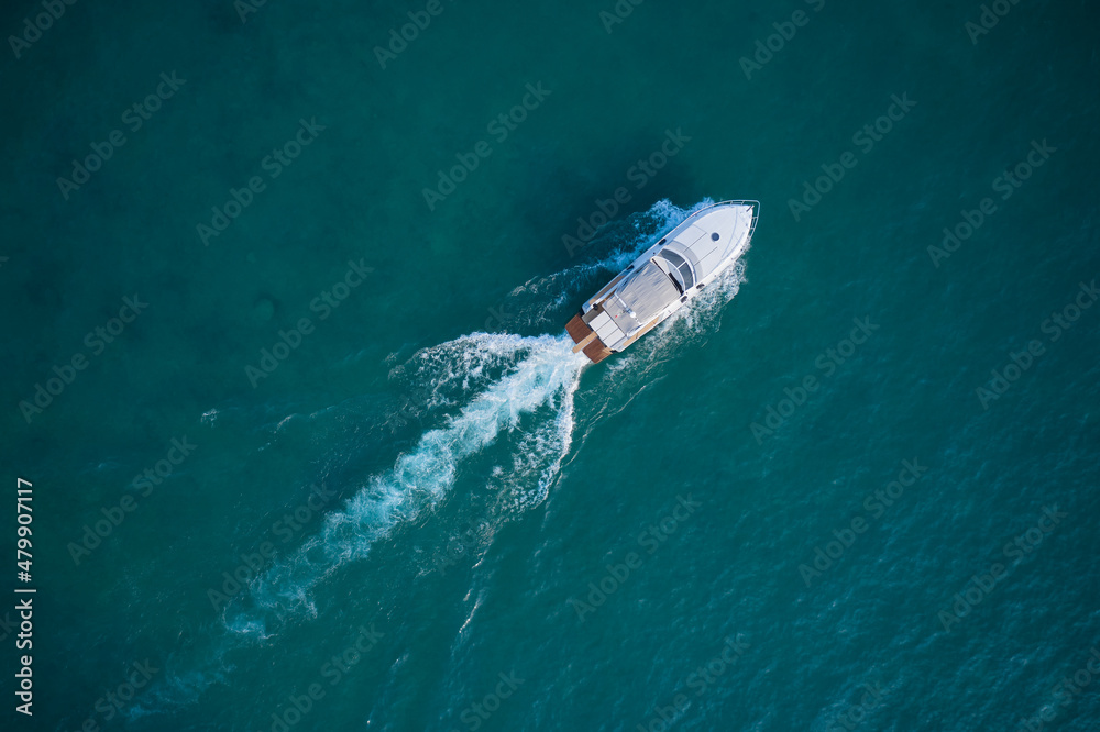 Obraz premium White yacht on the water top view. White boat on blue water aerial view. Boat in motion top view.