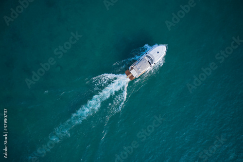White yacht on the water top view. White boat on blue water aerial view. Boat in motion top view.