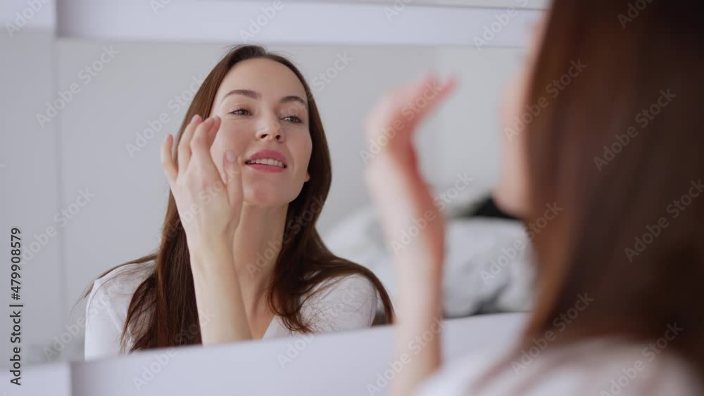 Glad female applying concealer and smiling Glad female applying concealer and smiling
