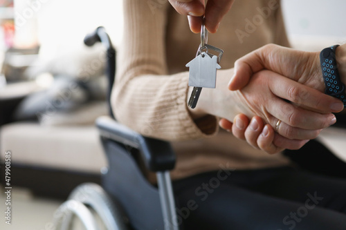 Realtor give keys from new accommodation to woman in wheelchair photo
