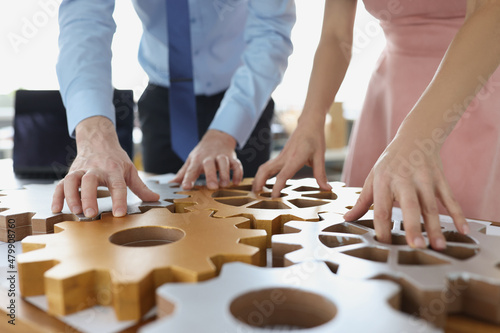 Business people making whole picture of wooden gears on workplace together in office