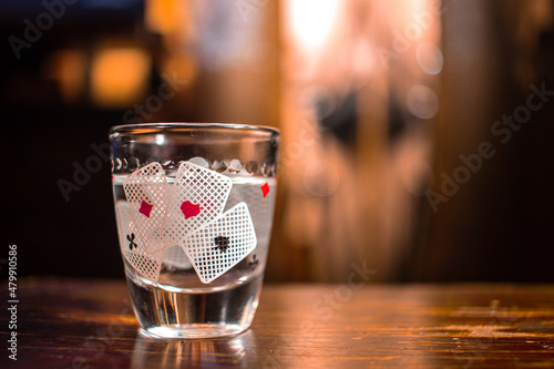 Glass of alcohol with a picture of playing cards on a wooden table