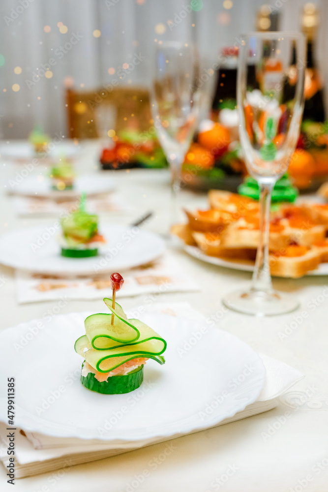 Festive canapes with salmon and cucumber in the form of a Christmas tree on a family holiday table. Banquet, buffet