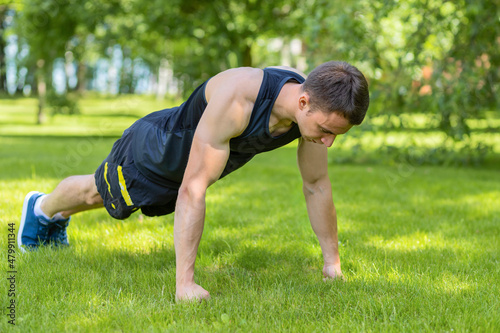 young man doing workout in park outdoor. muscular guy warming up and stretching before training. sport, fitness and healthy lifestyle concept.
