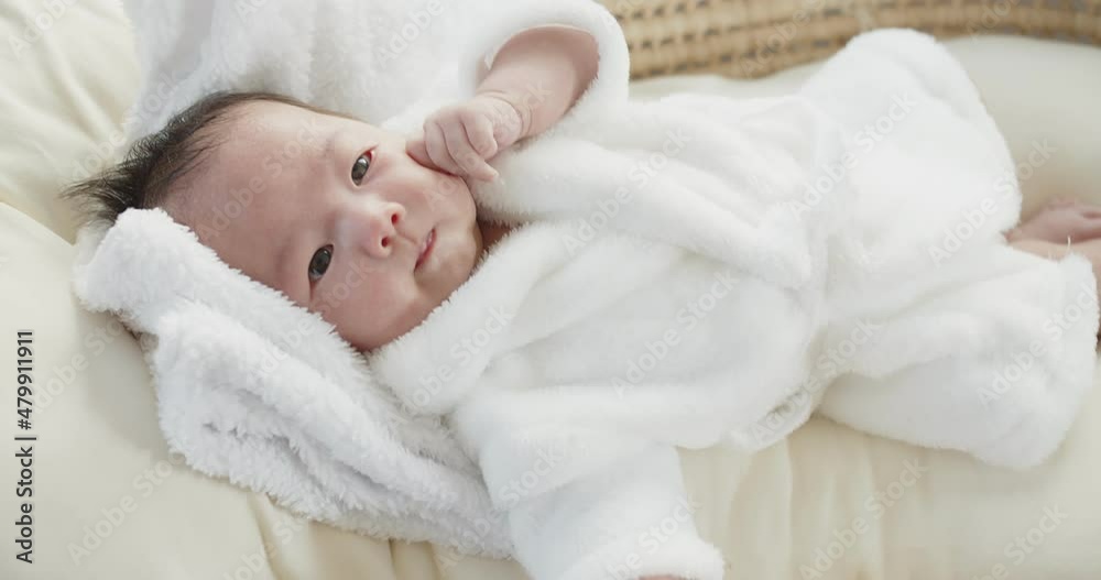 Portrait close up pretty Asian newborn baby infant girl in white bathrobe lying bed in a basket at home with eyes open, children, parenthood, childhood, life, maternity, love concept Portrait close up pretty Asian newborn baby infant girl in white bathrobe lying bed in a basket at home with eyes open, children, parenthood, childhood, life, maternity, love concept