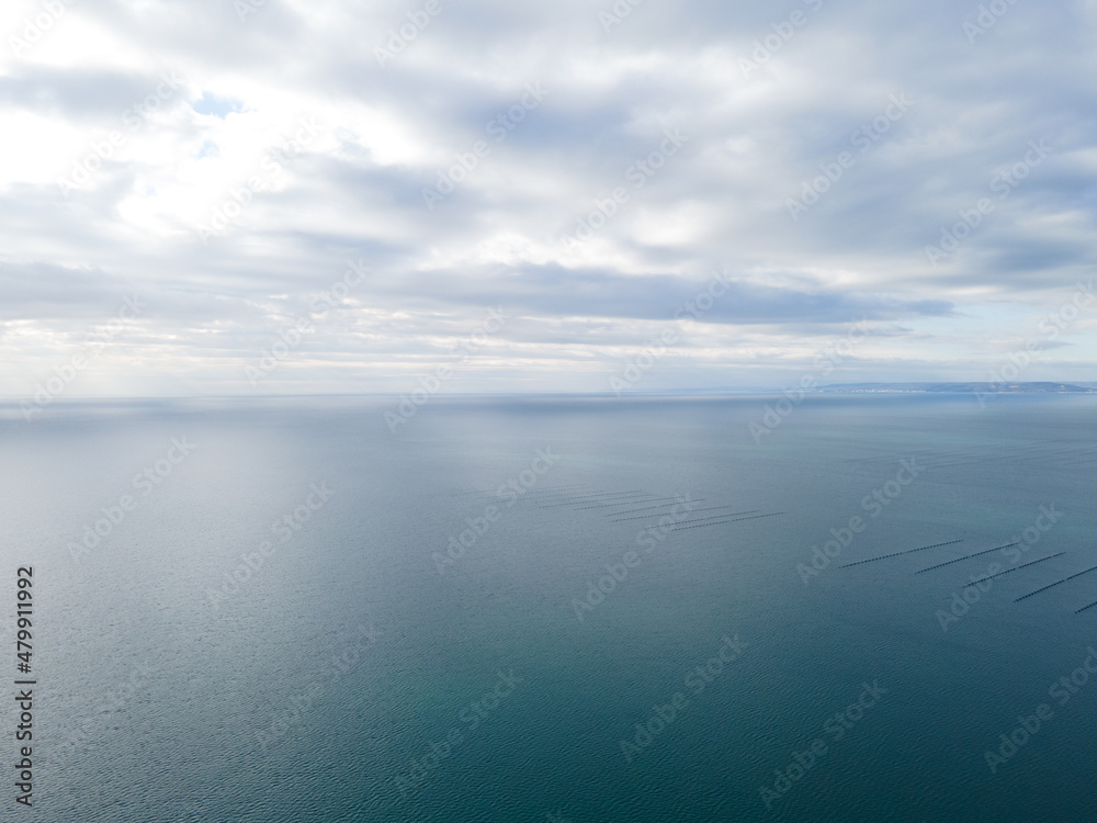 Aerial view over the sea with beautiful gray clouds illuminated by the sun