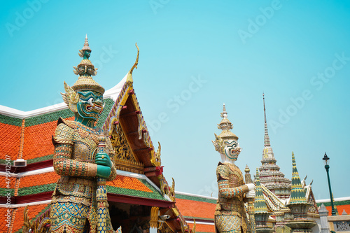 Two Giant guardian statue at Temple of the Emerald Buddha or Wat Phra Kaew in Bangkok, Thailand. Thai buddhist temple. Famous place and landmark of tourism. Ant view. Blue sky in Sunshine day. © APIAPIJAH