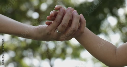 4K Video slow motion mom and daughter holding hand with green park background. Concept of family connection of mother and kids. photo