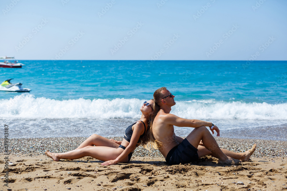 Young attractive man in sunglasses is resting in the pool on summer vacation. The guy in the pool by the hotel
