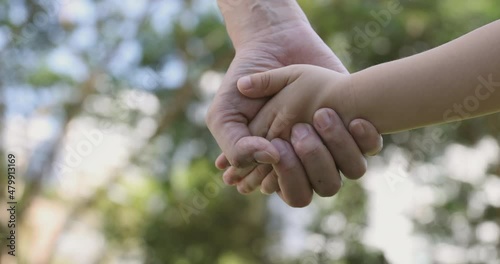 4K Video slow motion mom and daughter holding hand with green park background. Concept of family connection of mother and kids.