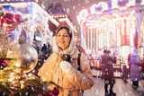 Happy young woman with cup hot coffee, Christmas market with bokeh light evening. Winter vacations in Red square Moscow, Russia