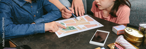 Tablou pe pânză Mother explaining to her children the assembly point map while preparing emergen
