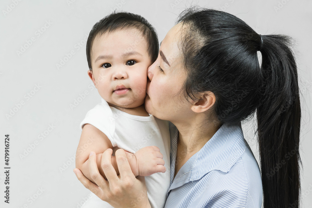 Selective focus Beautiful mom kissing on the cheek newborn with love and caring, Mother showing love to toddler with kiss on cheek. Selective focus Beautiful mom kissing on the cheek newborn with love and caring, Mother showing love to toddler with kiss on cheek.