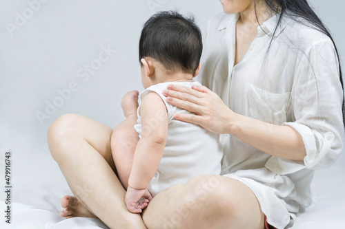 Fotografie Selective focus on Mother's hand is belching for infant baby by stroking the back with a hand after breastfeeding on bed at home